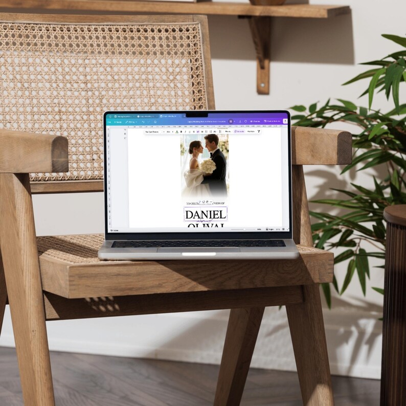 Peut inclure: Un ordinateur portable affichant une maquette de faire-part de mariage avec un couple en tenue de c&eacute;r&eacute;monie. L'invitation comprend les noms "DANIEL" et "OLIVIA" en police serif. L'ordinateur est pos&eacute; sur une chaise en bois avec une assise tress&eacute;e, avec une plante en arri&egrave;re-plan.
