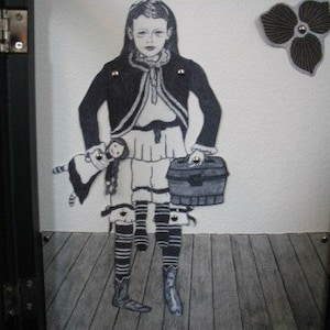 May include: A black and white illustration of a girl wearing a long-sleeved jacket and a skirt. She is holding a small doll and a suitcase. The background is white with a black and white flower.