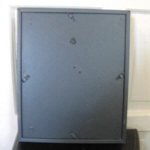 May include: A dark gray picture frame with a matte finish. The frame has a simple design and is made of wood.