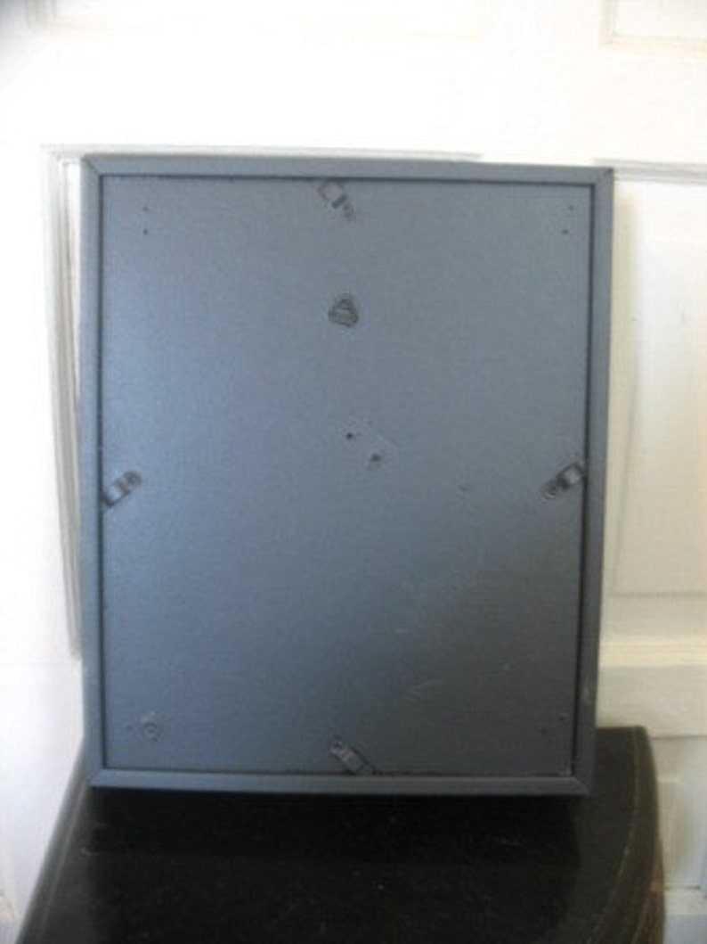 May include: A dark gray picture frame with a matte finish. The frame has a simple design and is made of wood.