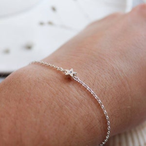 A wrist is shown with a single star bracelet. It is shown from a different angle to shown that the star is quite thick with the chain going through the middle. The star can turn on the chain but doesn't slide along it.
