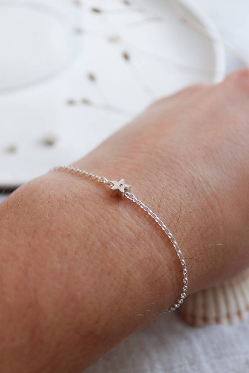 A wrist is shown with a single star bracelet. It is shown from a different angle to shown that the star is quite thick with the chain going through the middle. The star can turn on the chain but doesn't slide along it.