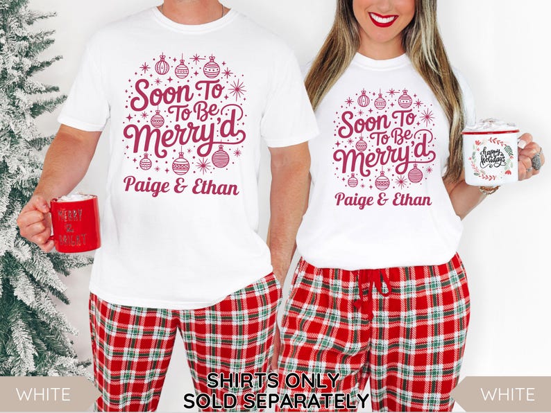 May include: White t-shirts with a festive design that reads "Soon To Be Merry'd" in burgundy, paired with red plaid pajama pants. The design includes ornaments and the names "Paige & Ethan". A red mug is held in each hand.