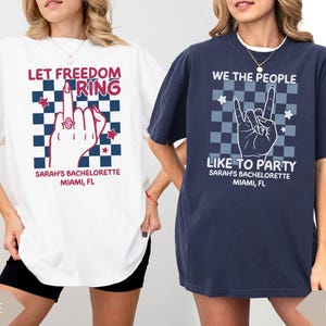 May include: Two oversized t-shirts, one white and one navy, with graphic designs. The white shirt says "LET FREEDOM RING" with a hand gesture and text "SARAH'S BACHELORETTE MIAMI, FL". The navy shirt says "WE THE PEOPLE LIKE TO PARTY" with a hand gesture and text "SARAH'S BACHELORETTE MIAMI, FL".