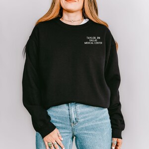 May include: Black sweatshirt with the text "TAYLOR, RN DALLAS MEDICAL CENTRE" in white.