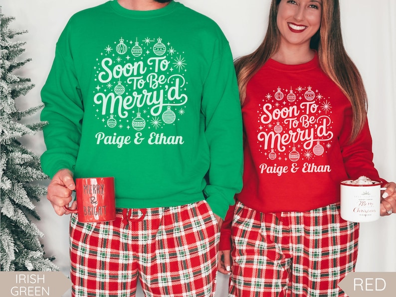 May include: Green and red Christmas-themed sweatshirts with the text "Soon To Be Merry'd" and the names "Paige & Ethan". The sweatshirts are paired with red and white plaid pajama pants. One person holds a red mug that says "Merry & Bright", and the other holds a white mug.
