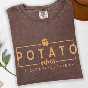 May include: Espresso brown t-shirt with a cartoon potato graphic and the text "POTATO vibes ALL DAY EVERY DAY".