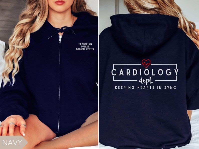 May include: Navy blue zip-up hoodie with a white graphic that says "Cardiology dept. Keeping hearts in sync" with a red heart and EKG line. The left side of the hoodie has white text that says "Taylor, RN Dallas Medical Center".