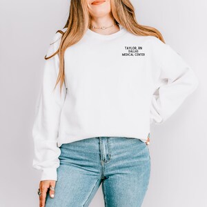 May include: White sweatshirt with the text "TAYLOR, RN DALLAS MEDICAL CENTER" printed on the front.