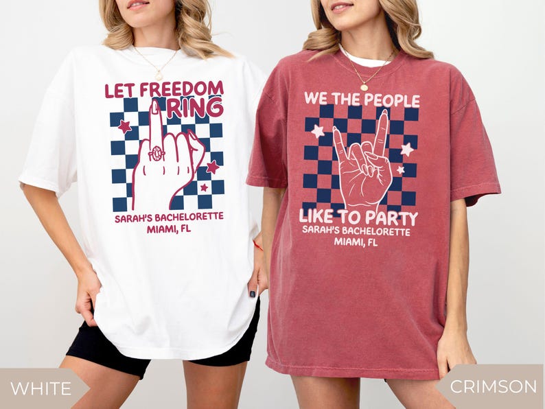 Two women wearing oversized Comfort Colors t shirts in white and crimson colors with patriotic graphic designs for a 4th of July bachelorette party. One shirt reads “Let Freedom Ring” with a hand graphic and custom name and location text. The other shirt reads “We the People Like to Party” with a rock hand gesture design. Styled for a summer girls trip or patriotic bach celebration.