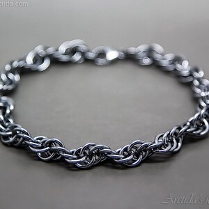 May include: A silver chain bracelet with a woven design. The bracelet is made of metal and has a polished finish.