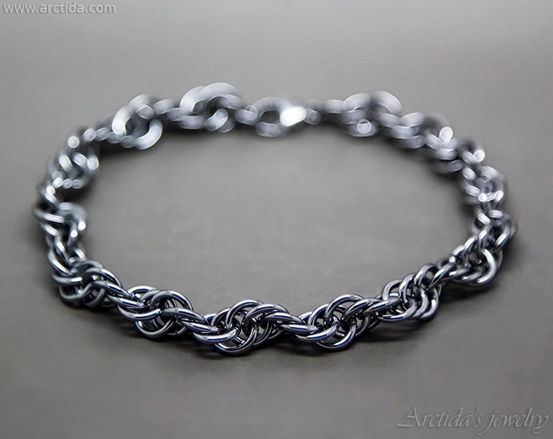 May include: A silver chain bracelet with a woven design. The bracelet is made of metal and has a polished finish.