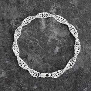 May include: A silver chain necklace with a unique, intricate design. The chain is made of small, interconnected rings that create a woven pattern. The necklace is approximately 18 inches long and has a lobster claw clasp.