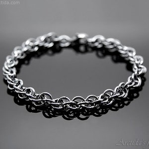 May include: A silver chain bracelet with a simple, classic design. The bracelet is made of interlocking metal rings.