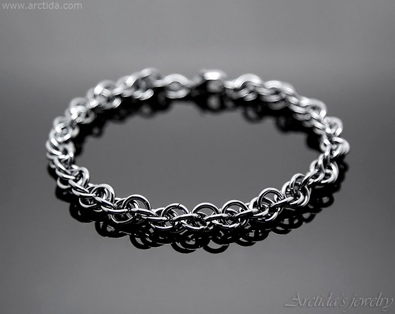 May include: A silver chain bracelet with a simple, classic design. The bracelet is made of interlocking metal rings.