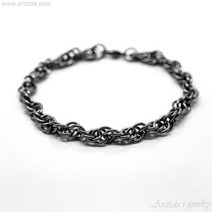 May include: A black metal bracelet with a twisted chain design.