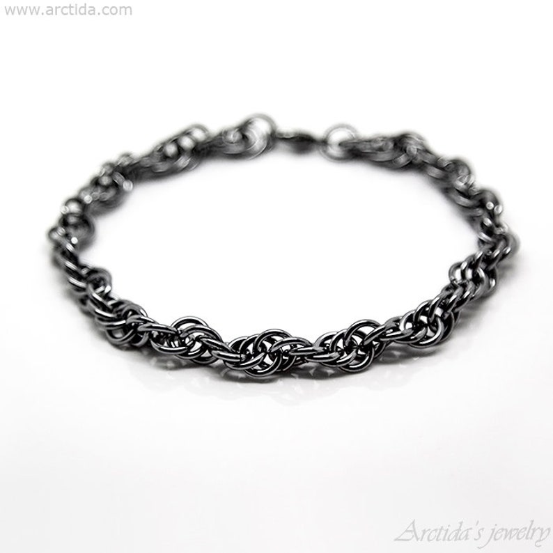May include: A black metal bracelet with a twisted chain design.