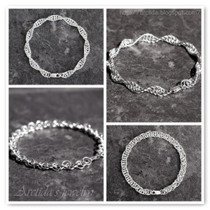 May include: Four silver chain necklaces with different styles and designs. The necklaces are displayed on a gray textured background. The text "Arctida's jewelry" is visible in the bottom left corner.