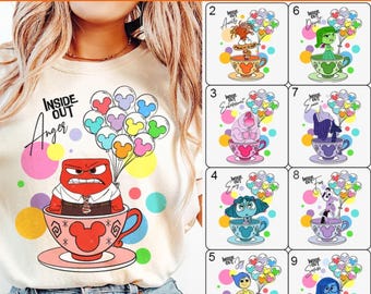 Op de afbeelding: Een wit T-shirt met een kleurrijke afbeelding van een personage uit de film Inside Out. Het personage zit in een theekopje met Mickey Mouse oren. De tekst "Inside Out Woede" staat op het shirt gedrukt.