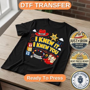 May include: A black t-shirt featuring a graphic print with the text I KNEW IT I KNEW YOU, a red cowboy hat, a yellow sheriff badge, red cowboy boots, alphabet blocks, and a beaded bracelet with the text YOU FOREVER, plus three circular labels.