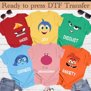 May include: Six different colored t-shirts with cartoon faces from the movie Inside Out. The shirts are red, yellow, green, blue, pink, and orange. The faces are Anger, Joy, Disgust, Sadness, Embarrassment, and Anxiety.