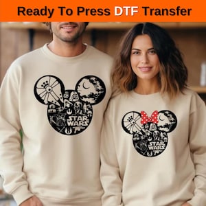 Puede incluir: Dos sudaderas beige con un diseño de Mickey Mouse en blanco y negro con personajes de Star Wars. El diseño incluye el Halcón Milenario, Darth Vader, Yoda y las palabras "Star Wars". Una sudadera tiene un lazo rojo en las orejas de Mickey.