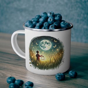 May include: White enamel mug with a silver rim, filled with blueberries. The mug features a whimsical illustration of a child holding a lantern in a moonlit field with butterflies. The mug is sitting on a wooden surface.