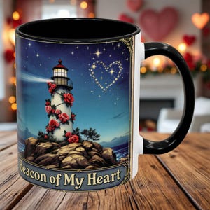 May include: White ceramic coffee mug with a black handle. The mug features a lighthouse with red roses and a starry night sky. The text "Beacon of My Heart" is printed on the bottom of the mug.
