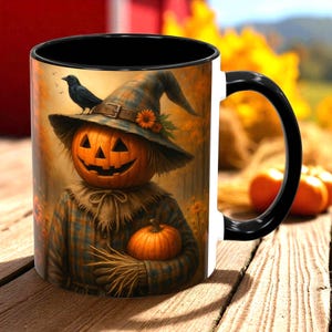 May include: A white ceramic mug with a black handle and rim. The mug features a Halloween-themed design of a scarecrow with a pumpkin head, wearing a plaid shirt and hat, and holding a small pumpkin. A black crow sits on the hat.