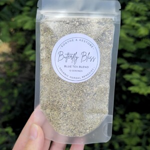 May include: A clear, resealable pouch filled with a blue tea blend. The pouch has a circular label with the text "Butterfly Bliss" and "Blue Tea Blend." The label also includes the phrases "Soothe & Restore" and "Organic Herbal Remedies."