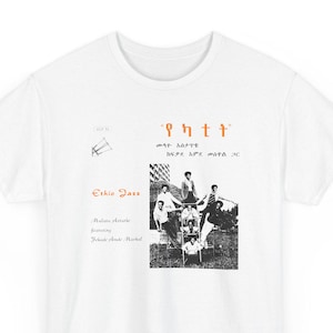 May include: White t-shirt featuring a black and white image of a group of people, with text in orange and black. The text includes "Ethio Jazz" and other text in a different language.