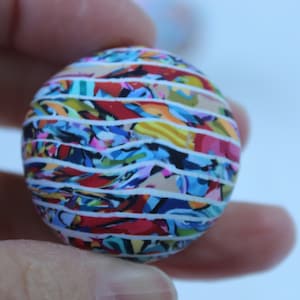 以下が含まれることがあります： 白地にカラフルなストライプ模様の球体。赤、青、黄、緑など様々な色が使われています。