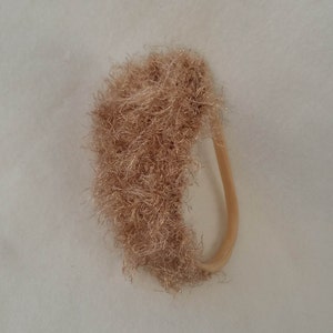 May include: A brown fuzzy hair scrunchie with a brown elastic band.