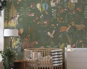 May include: A nursery with a forest-themed wallpaper featuring woodland animals like deer, foxes, and owls. A wooden crib and a white dresser with a giraffe design are in the room. A hanging mobile and a floor lamp with a white shade are also visible.