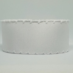 May include: A roll of white grosgrain ribbon with a scalloped edge. The ribbon has vertical ribbed texture and is suitable for crafts, gift wrapping, or decorative purposes. The ribbon is approximately 2 inches wide.