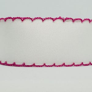 May include: White ribbon with a textured surface and a scalloped edge. The edge is trimmed with a bright pink, decorative stitching. The ribbon is a cylinder shape and is suitable for crafts and gift wrapping.