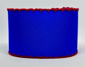Op de afbeelding: Een blauw lint met een rode gecrochete rand. Het lint is effen gekleurd en heeft een gladde textuur.