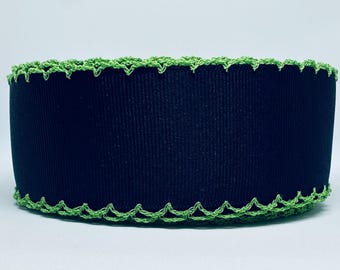 Op de afbeelding: Zwart lint met een groene gehaakte rand. Het lint is ongeveer 2,5 cm breed.