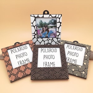 May include: Four wooden Polaroid photo frames with different geometric patterns. The frames are all the same size and have a black and white photo of two people in the top frame.