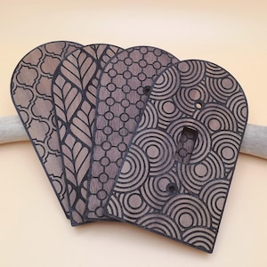 May include: Four wooden light switch covers featuring different geometric patterns. The designs include a honeycomb pattern, a circular design, a geometric pattern, and a leaf pattern. The covers are all dark brown and have a slightly textured finish.