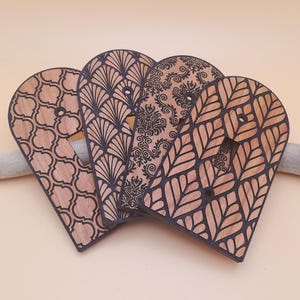 Könnte beinhalten: Vier Holz-Lichtschalterabdeckungen mit verschiedenen geometrischen Mustern. Die Abdeckungen sind in Braun- und Schwarztönen gehalten.