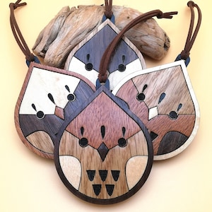 May include: Four wooden ornaments shaped like owls with intricate details and different wood tones. Each owl has a loop for hanging.