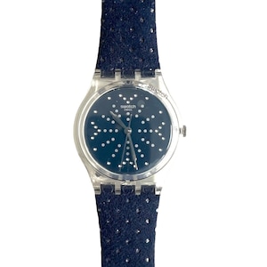 May include: A silver Swatch watch with a blue face and a black patterned leather band. The face has a silver-tone starburst design with white dots.