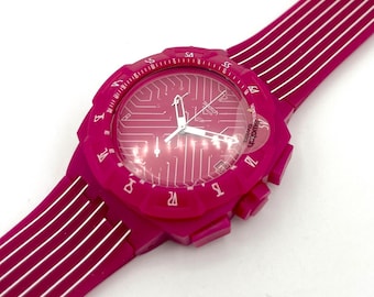 Puede incluir: Un reloj de pulsera rosa brillante con una correa a juego. La esfera del reloj presenta un diseño de placa de circuito y agujas blancas. La correa tiene rayas blancas. Un accesorio de moda.