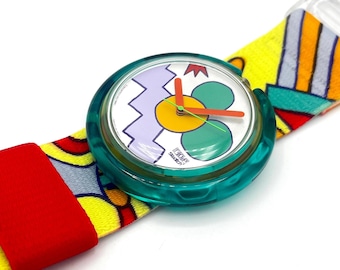 May include: A vintage Swatch watch with a teal case and a colorful patterned band. The watch face features a flower design with green petals, a yellow center, and orange hands. The band is yellow with red and blue accents.