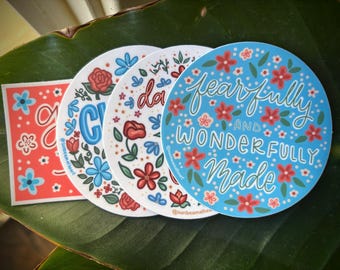 May include: A selection of circular stickers with floral patterns and positive affirmations. The stickers are in various colours, including red, blue, and white. One sticker displays the phrase "fearfully and wonderfully made."