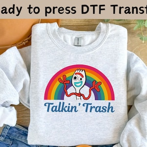 May include: A gray sweatshirt with a rainbow and a cartoon character of a fork with a face and arms. The text "Talkin' Trash" is printed below the character.