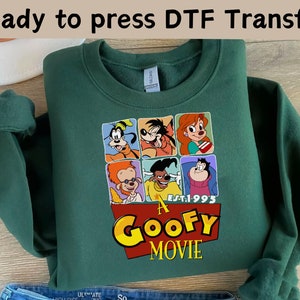 Op de afbeelding: Groen sweatshirt met een grafische print van personages uit de film "Een Goofy Movie". De grafiek bevat de tekst "Est. 1995" en de titel van de film.