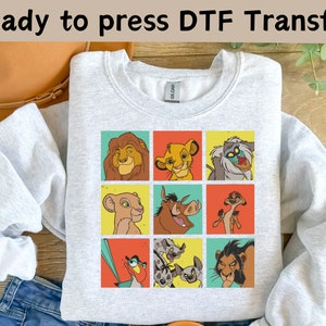May include: A gray sweatshirt with a colorful graphic of characters from the Lion King. The graphic features Simba, Nala, Mufasa, Pumbaa, Timon, and Scar in a grid pattern. The text "Ready to press DTF Transfer" is at the top of the image.