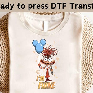 以下が含まれることがあります： 青い風船を持った漫画のキャラクターが描かれた白いTシャツ。キャラクターは赤い髪で、赤と白のストライプのシャツを着ています。キャラクターの下には「I'm FIINE」という文字が印刷されています。